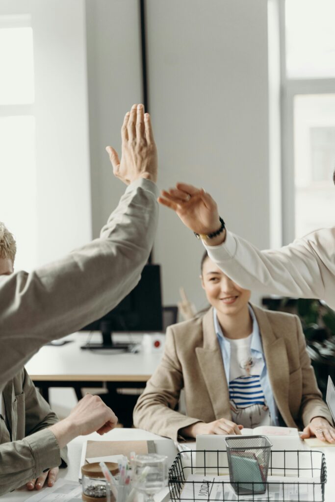 pexels-photo-7430340-7430340 Colleagues in an office exchanging a high five, symbolizing teamwork and success.